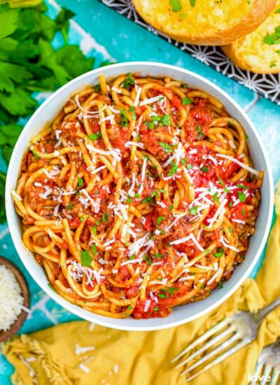 A bowl of instant pot spaghetti on a blue background with yellow napkins.