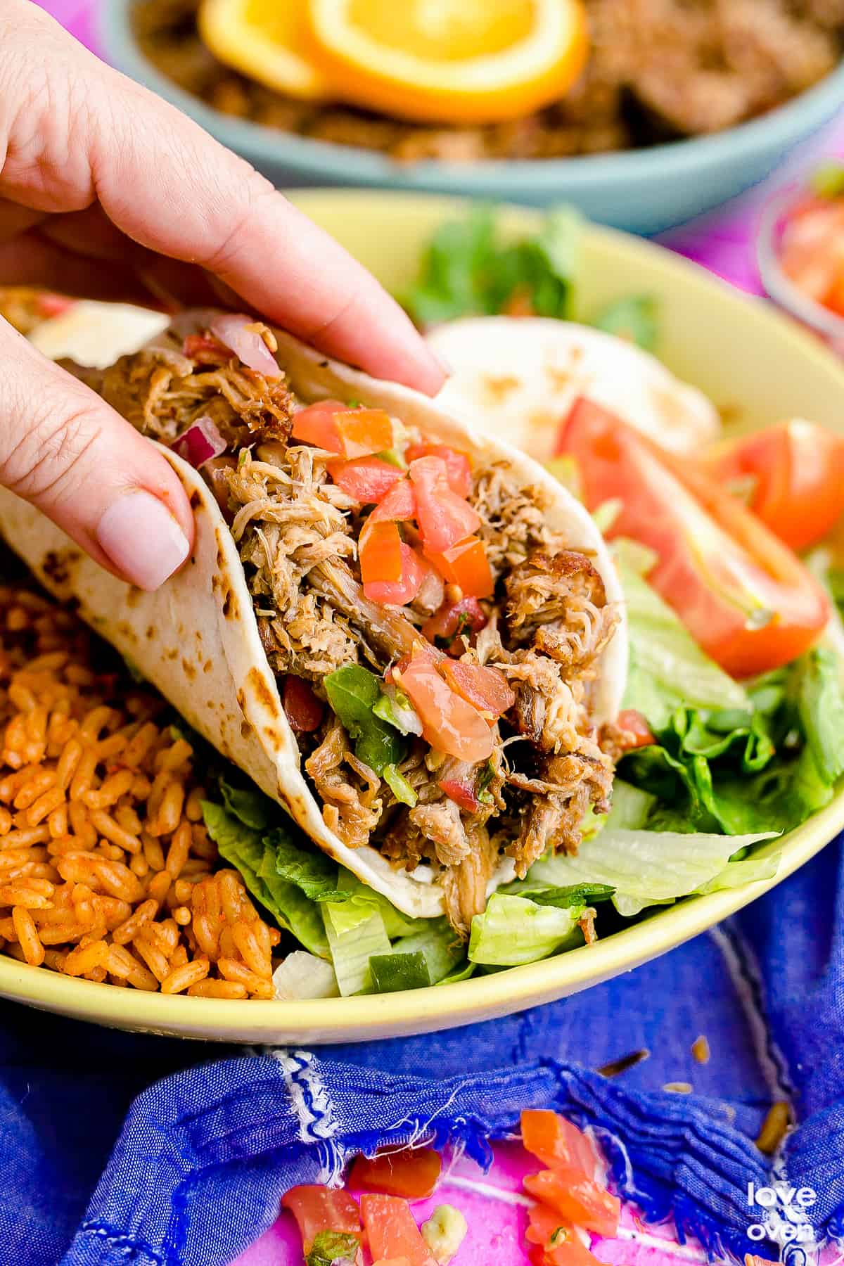 a hand picking up a pork carnita taco