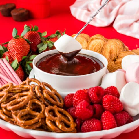A bowl of chocolate fondue surrounded by fondue dippers