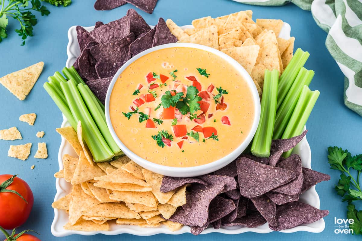 A bowl of velveeta cheese dip with chips around it.