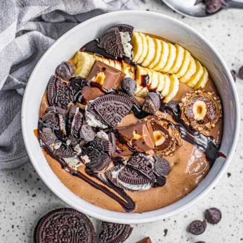 A chocolate smoothie bowl with bananas and toppings