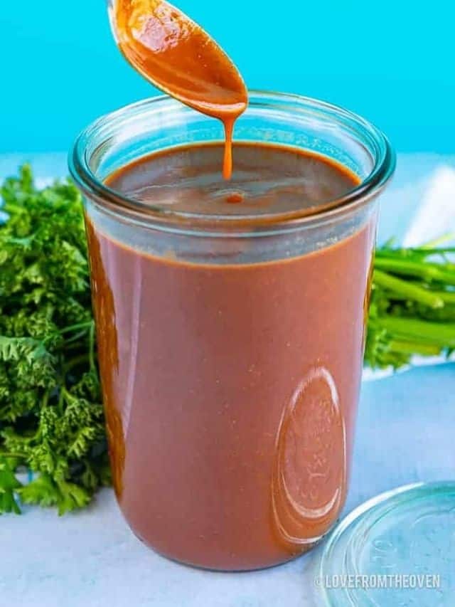 A jar of red Enchilada sauce scooped by a spoon