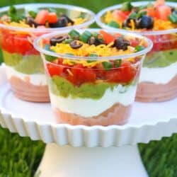 A photo of seven layer dip appetizer cups on a white stand