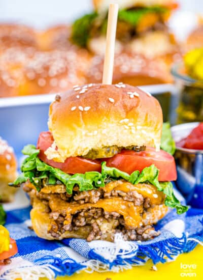 A cheeseburger slider on a blue and white tablecloth.