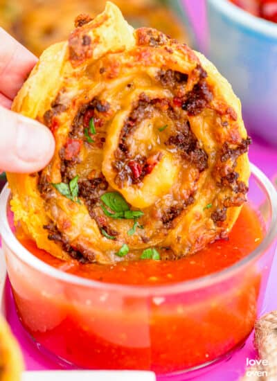 a taco pinwheel being dipped into salsa