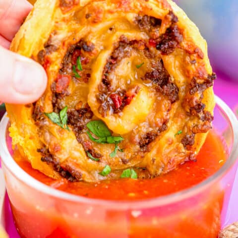 a taco pinwheel being dipped into salsa