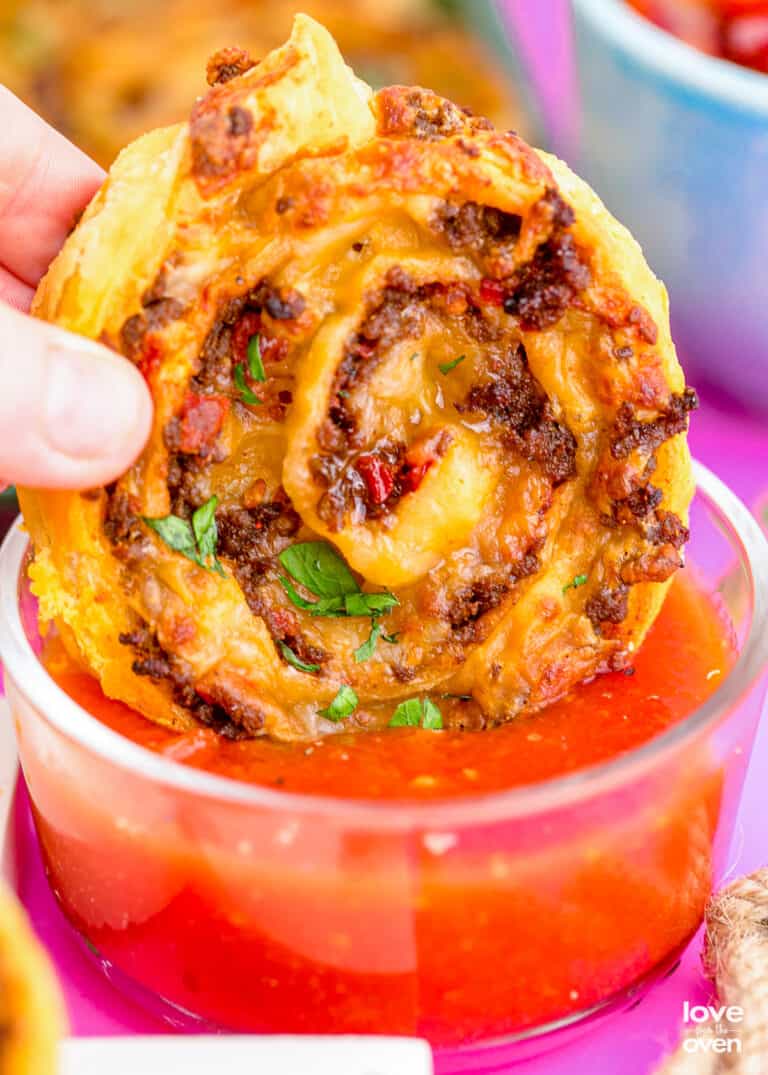 a taco pinwheel being dipped into salsa