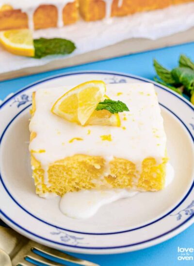 a slice of lemon cake with lemon glaze topped with lemon slices and mint on a plate