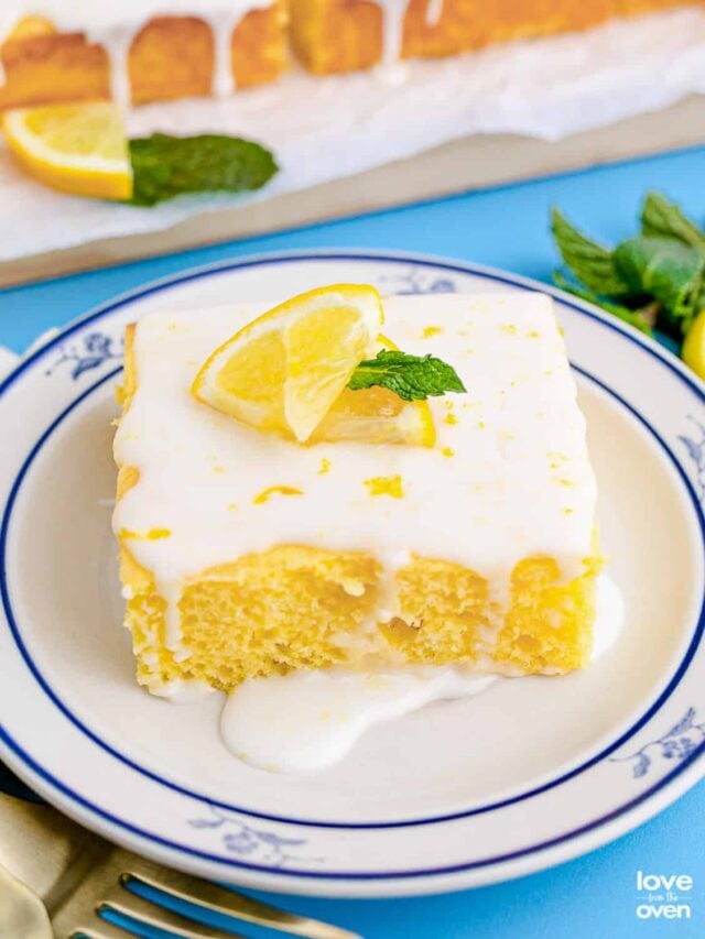 a slice of lemon cake with lemon glaze topped with lemon slices and mint on a plate