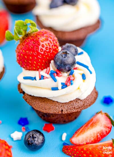 Brownie bites topped with frosting, berries and sprinkles.
