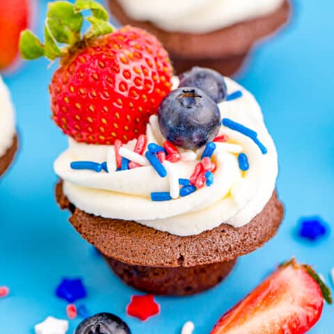 Brownie bites topped with frosting, berries and sprinkles.