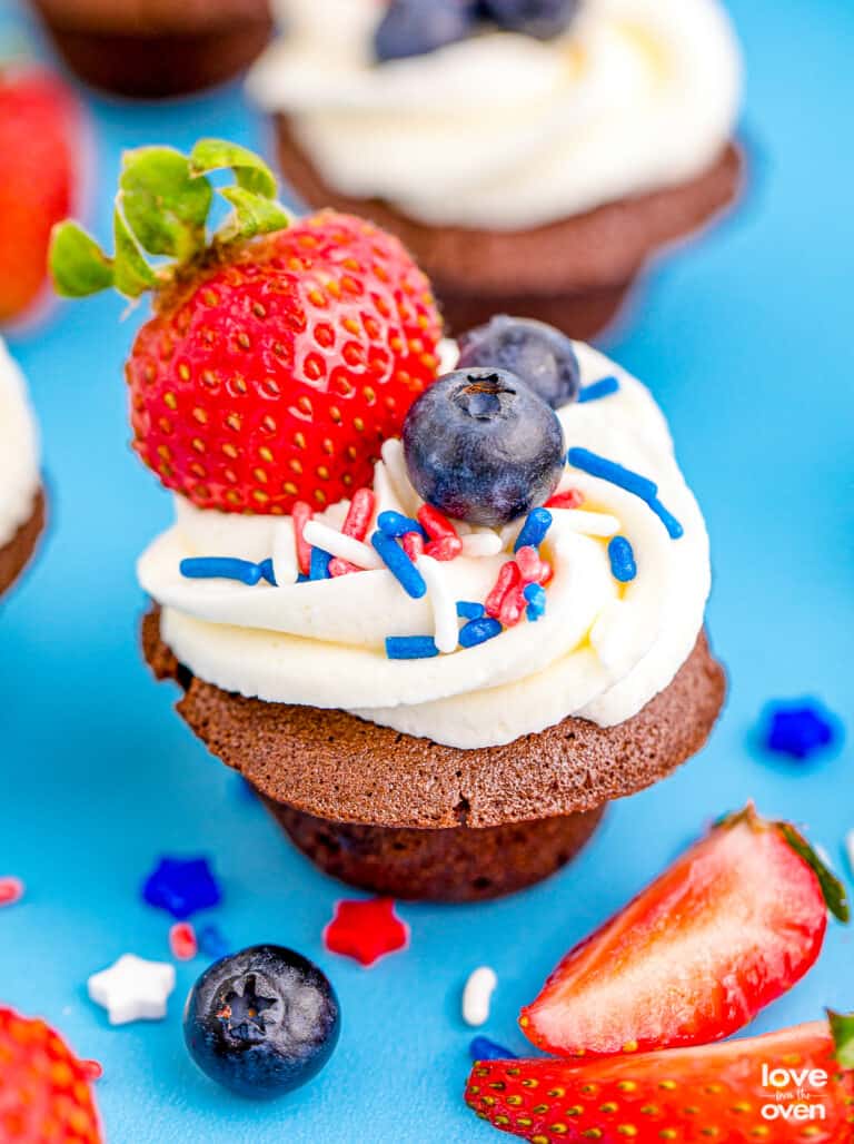 Brownie bites topped with frosting, berries and sprinkles.