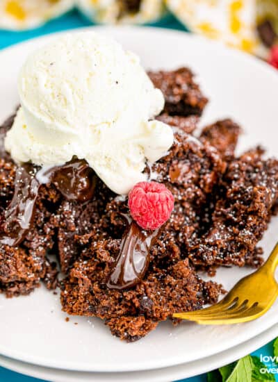 A serving of chocolate crock pot cake on a plate topped with ice cream.