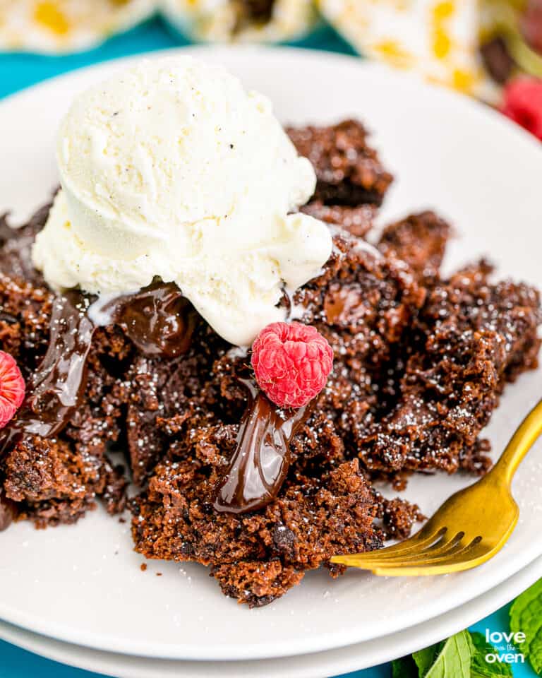 A serving of chocolate crock pot cake on a plate topped with ice cream.