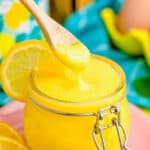 a jar of lemon curd with a spoon taking some out.