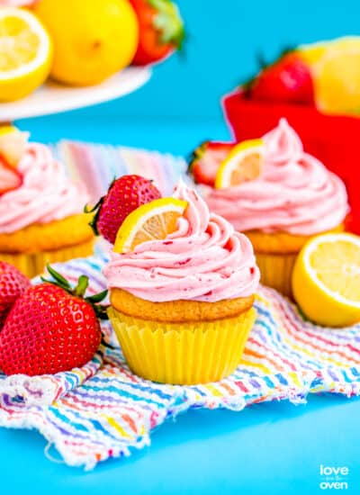 two strawberry lemon cupcakes on a blue background.