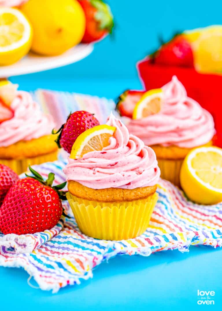 two strawberry lemon cupcakes on a blue background.