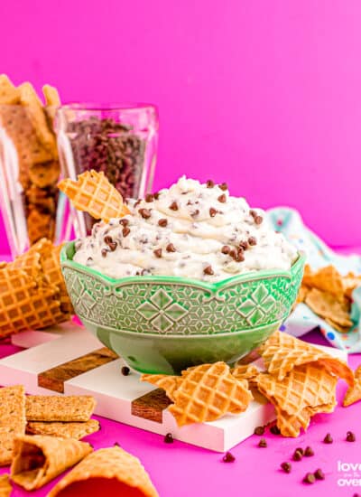 A bowl of cannoli dip with broken waffle cones around it.