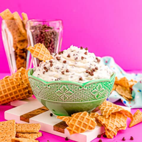 A bowl of cannoli dip with broken waffle cones around it.