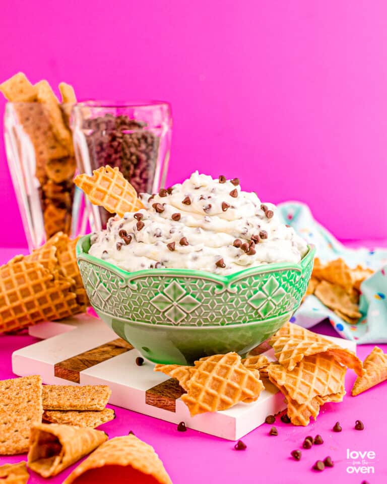 A bowl of cannoli dip with broken waffle cones around it.