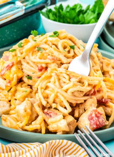 A plate of rotel chicken spaghetti, with a fork scooping some up.