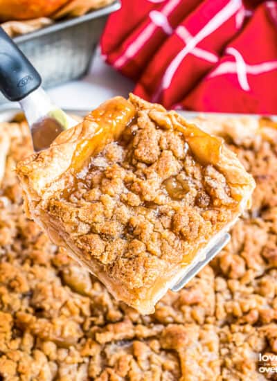 A slice of apple slab pie being cut out of a pie.