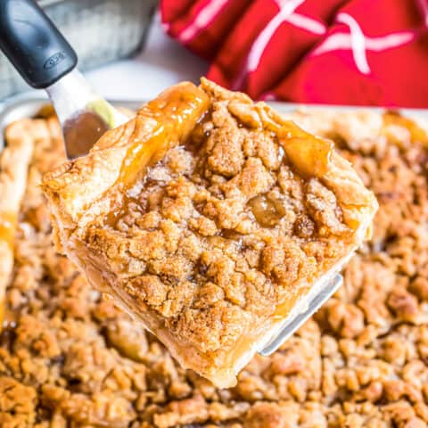A slice of apple slab pie being cut out of a pie.