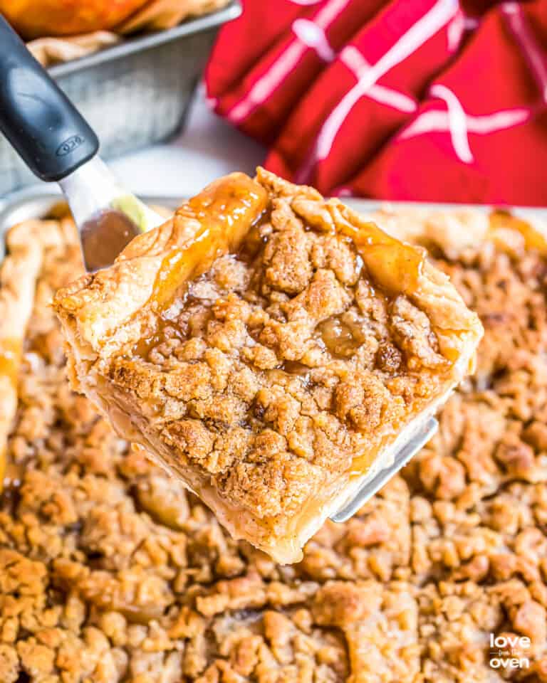 A slice of apple slab pie being cut out of a pie.