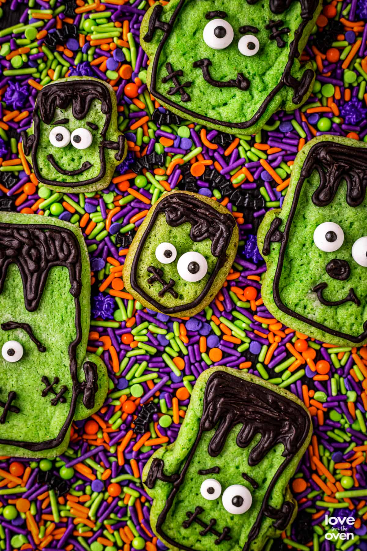 A bunch of halloween cookies on colorful sprinkles.