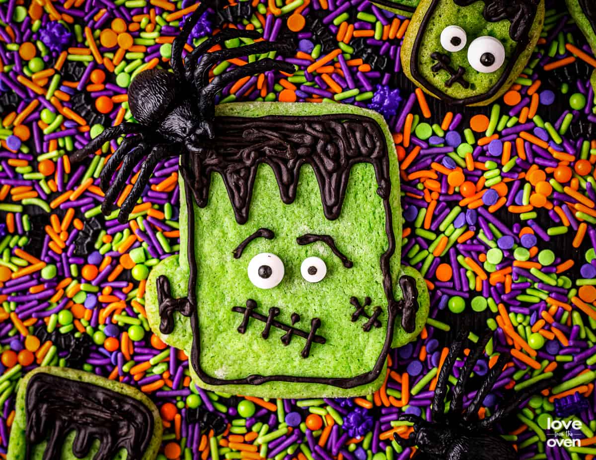 A Frankenstein halloween cookie surrounded by halloween sprinkles.