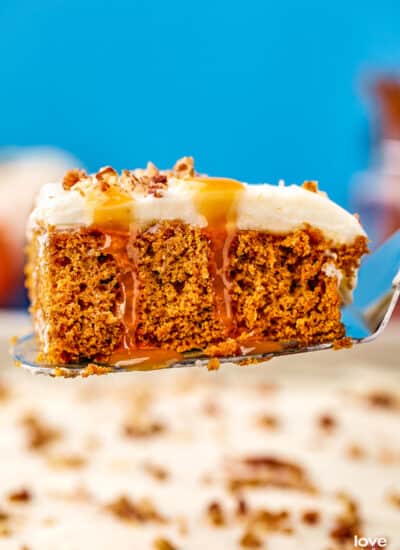 A pumpkin poke cake with caramel dripping down it, on a serving spatula.