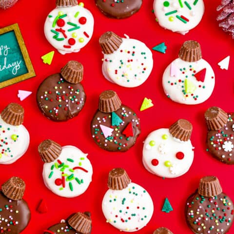 Chocolate covered ritz crackers that are decorated to look like ornaments laid out on a red background.