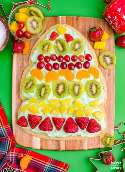 A Christmas tree fruit pizza on a wooden cutting board