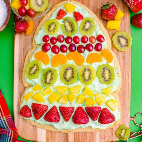 A Christmas tree fruit pizza on a wooden cutting board