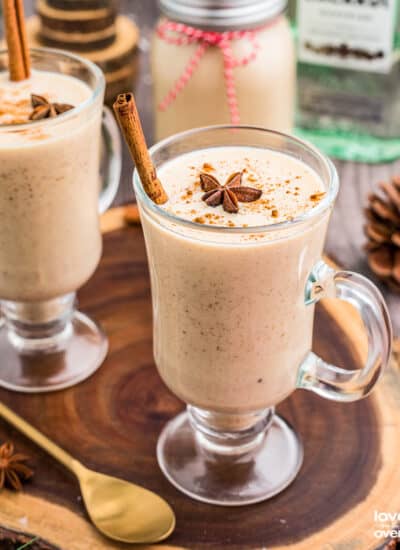 Two glasses of Coquito on a wooden slab.