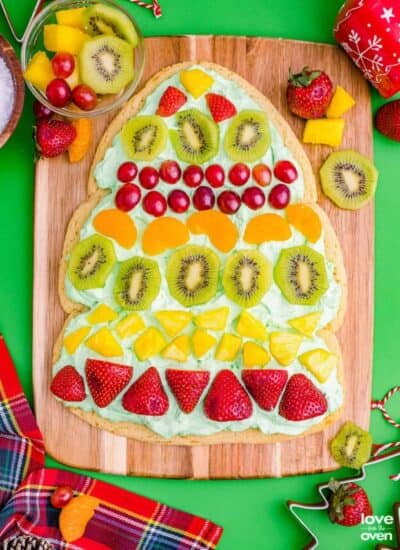 A Christmas tree fruit pizza on a wooden cutting board