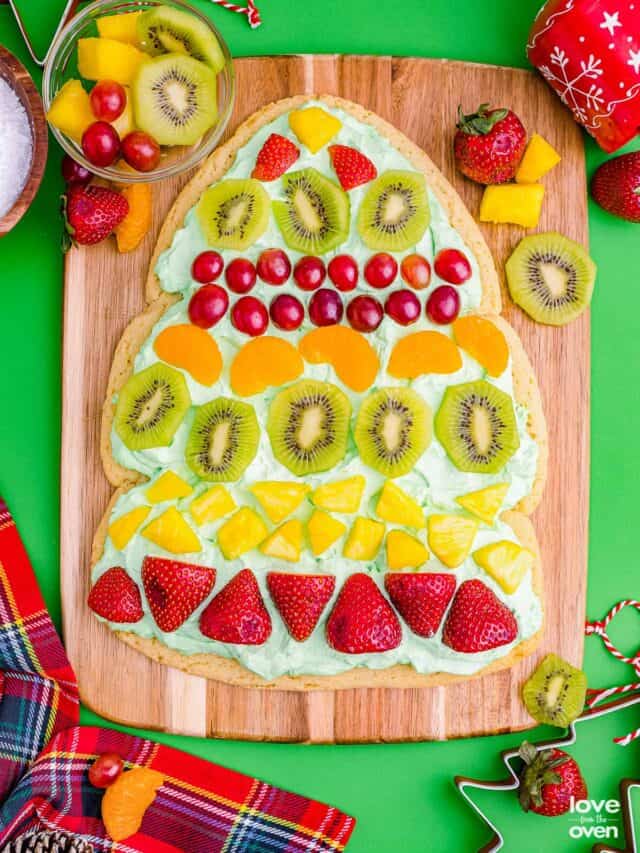 A Christmas tree fruit pizza on a wooden cutting board