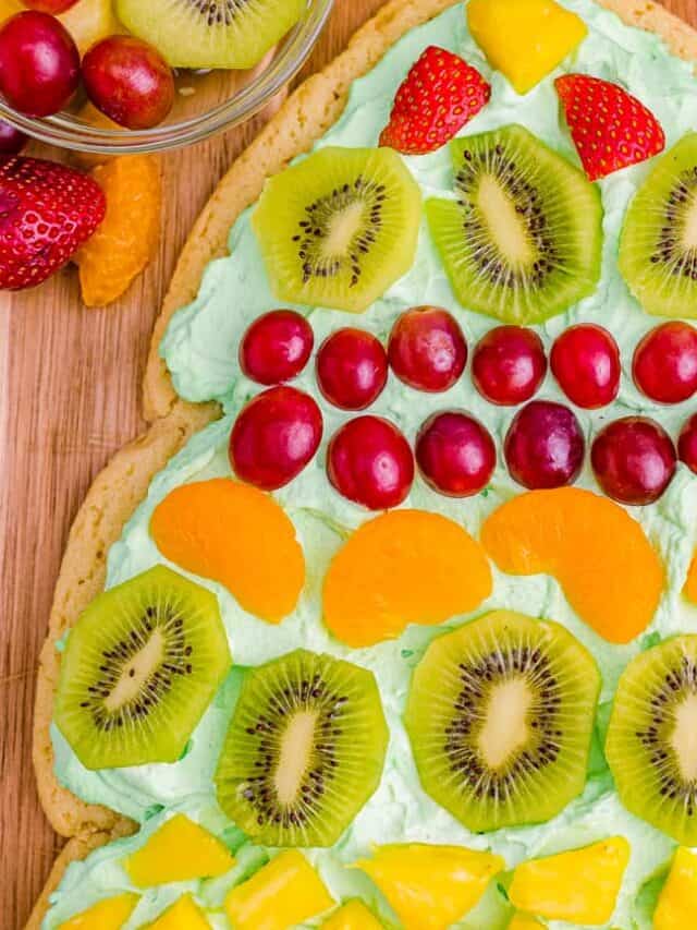 A Christmas tree fruit pizza on a wooden cutting board