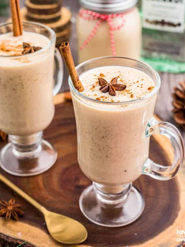 Two glasses of Coquito on a wooden slab.