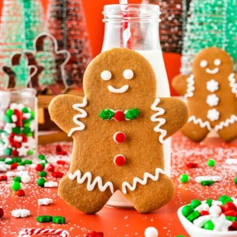 A gingerbread man cookie leaning on a small milk bottle