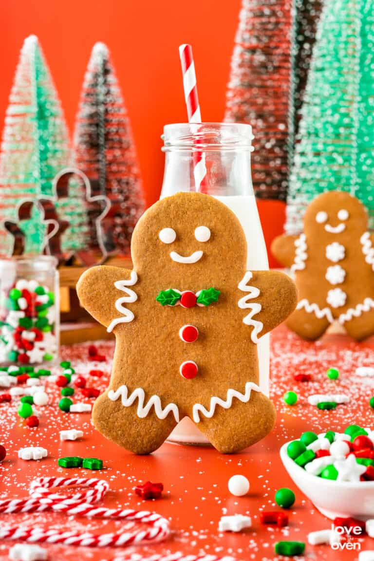 A gingerbread man cookie leaning on a small milk bottle