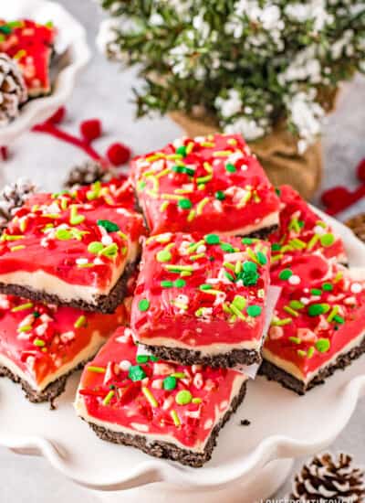 Peppermint fudge, topped with sprinkles, on a white fluted cake stand.