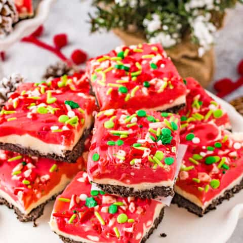 Peppermint fudge, topped with sprinkles, on a white fluted cake stand.