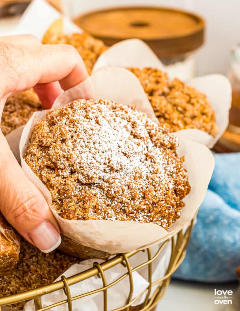 A hand grabbing a pumpkin streusel muffin from a basket.