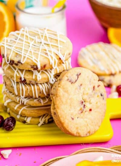 A stack of orange cranberry cookies on a pink board.