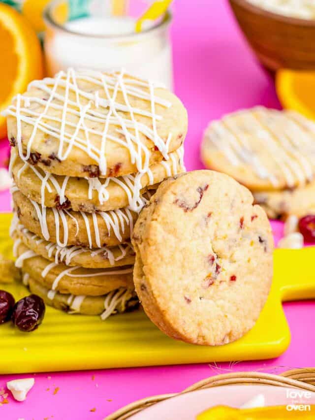 A stack of orange cranberry cookies on a pink board.