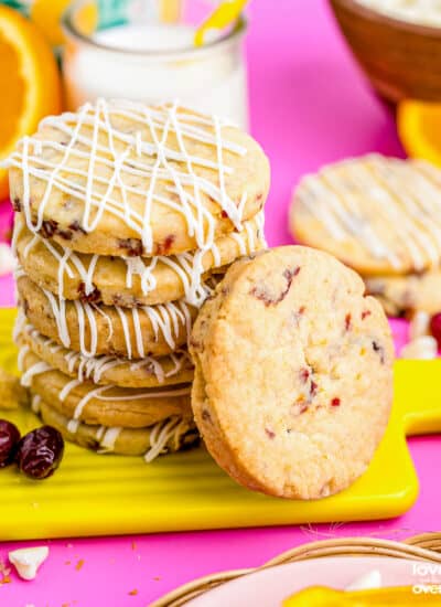 A stack of orange cranberry cookies on a pink board.
