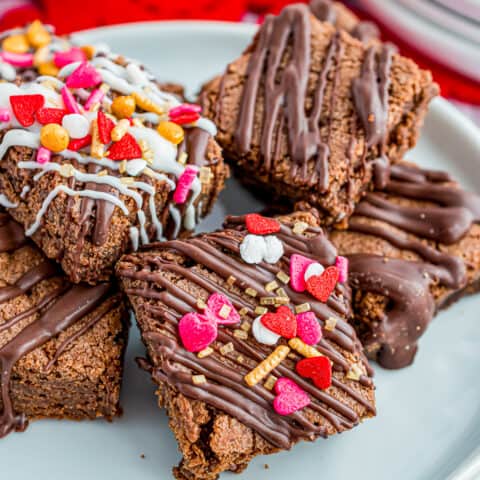 A plate of brownie bites with valentine sprinkles on them.