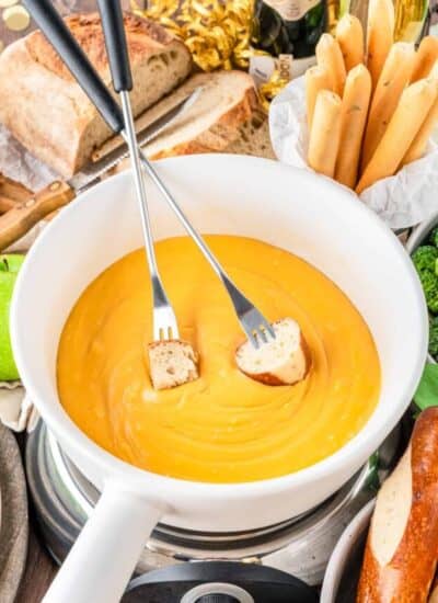 a bowl of cheese fondue with two fondue forks in it