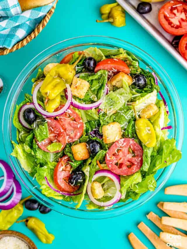 A copycat olive garden salad in a serving bowl on a blue table